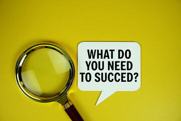 What do you need to succed? text on speech bluble with magnifying glass top view on yellow...