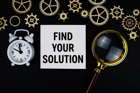 FYS - Find Your Solution text message on sticky note with magnifying glass and alarm clock on black background