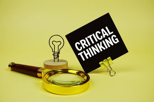 Critical Thinking text message on sticky note with magnifying glass on yellow background