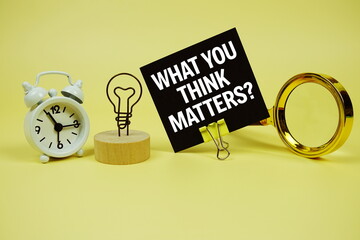 What You Think Matters? text on paper card with alarm clock and magnifying glass on yellow...