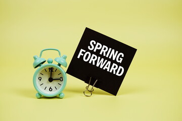 Spring Forward text message on paper card with alarm clcok on yellow background
