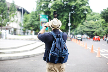 Traveler Man Doing Livestream Using Smartphone and Selfie Stick While Exploring City Street