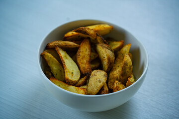 Crispy Roasted Potato Wedges with Seasoning in a Modern White Bowl. Fresh Hot Potato Wedges with Golden Brown Crust for Healthy Comfort Food