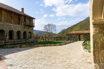 The courtyard of the Kvatakhevi monastery. Stone paths, green grass, bell tower, living quarters of...