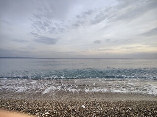 The Silent Shore: A Metaphor of Endless Horizons and Fleeting Waves, Where Pebbled Stillness Meets the Moody Sky, Reflecting a Timeless Serenity Amid the Calm Before the Storm in Nature&rsquo;s Unspoken.