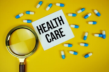 Healthcare text on sticky paper note with Medicine Capsule and Magnifying glass on yellow background