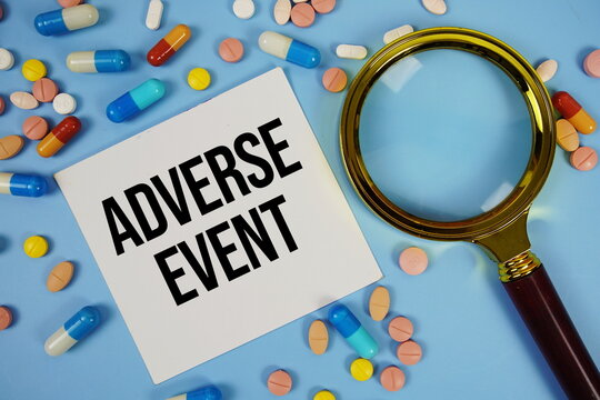 Adverse Event text on sticky note paper with Medicine and Maginfying glass on blue background