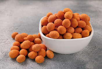 Spicy coated fried peanuts on gray background. Snacks and nuts.