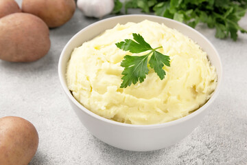 Mashed potatoes in white bowl on grey concrete background. Healthy food