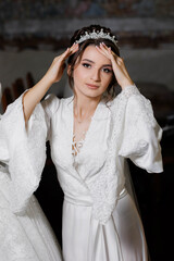 A woman wearing a white dress and a tiara. She is posing for a picture. The dress is long and...