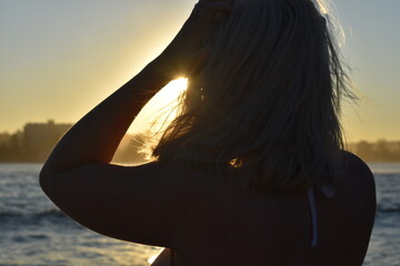 Fototapeta premium Girl on the beach at sunset silhouetted golden rays