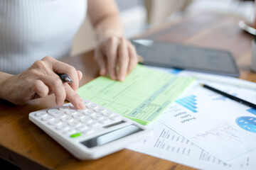 Woman is using a calculator to calculate information on a document