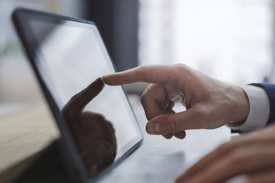 Closeup of male finger touching to modern digital tablet screen on desk on light blur office background