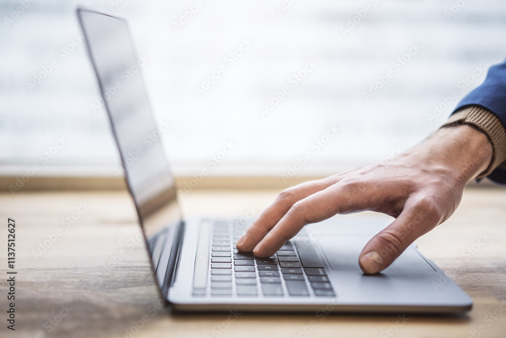 Poster the picture shows a close-up of a man's hands typing ona contemporary laptop keyboard, with a softly