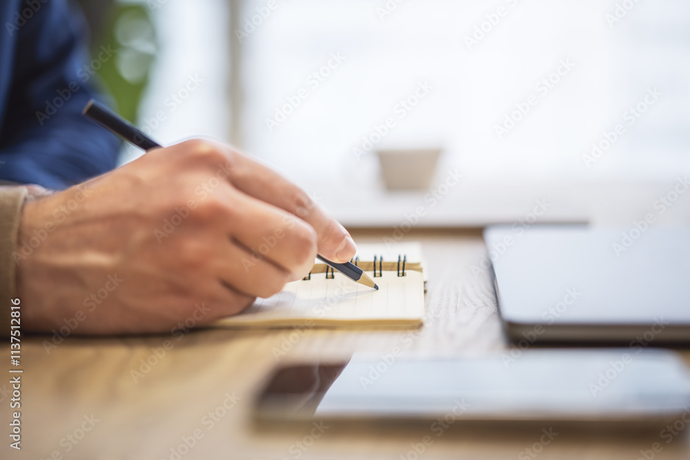 Aufkleber the image focuses on a man's hand scribbling in a notepad, set against a blurry scene