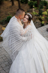 Naklejka premium A bride and groom are hugging each other, with the bride wearing a white dress and the groom wearing a white suit
