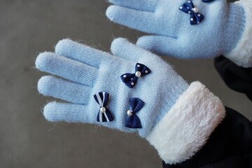 小学生の女の子向けの水色リボン付き手袋を、11歳の女の子が身につけている様子。