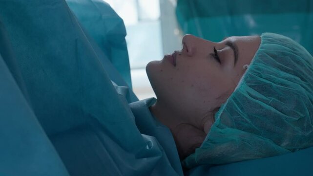 Close-up of a patient lying on the operating table wearing a surgical cap and drapes, under medical preparation. Concept of surgery, healthcare, childbirth, and patient care