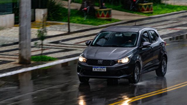 Grey Fiat Argo cruising city street in the rain, Hatchback in movement, high resolution