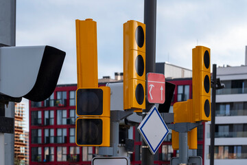 The image features bright yellow traffic lights and a red sign at a city intersection, emphasizing urban traffic management and safety in busy environments.
