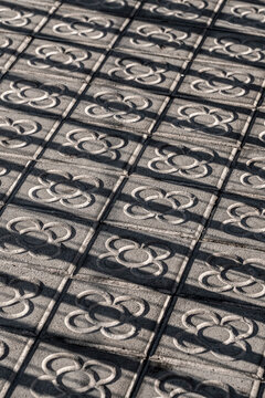 The patterned pavement reflects intricate designs and shadows, creating a striking visual interplay that emphasizes urban artistry and everyday life in Barcelona Spain