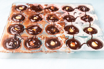 The nut mold is filled with tempered chocolate and ganache. The process of making homemade chocolates.