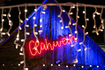 Gluewine shop with illuminated red and blue neon sign 