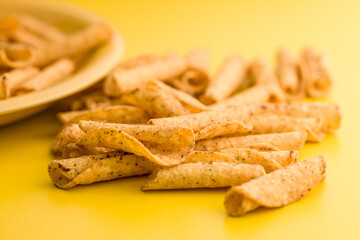 Rolled nachos tortilla chips on yellow background.