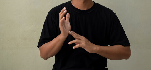 Young man showing gesture in sign language on gray background © syahrir