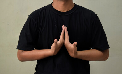 Young man showing gesture in sign language on gray background