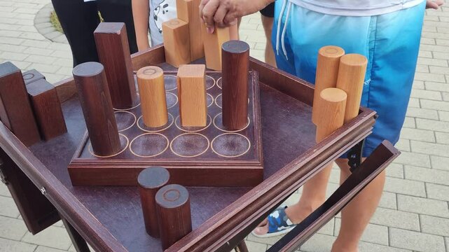 A wooden board game made from round and square pieces where you need to assemble a row of identical pieces, close-up