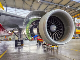 Aircraft engine servicing in hangar, with various tools and equipment visible. High quality photo