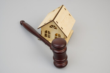 Wooden judge gavel and house model on gray background.