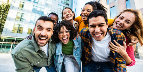 Multicultural young people smiling at camera together outside - Happy group of friends having fun walking on city street - Youth community concept