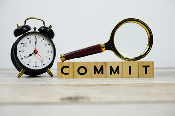 Time to Commit with wooden blocks alphabet letters and Magnifying glass on wooden background