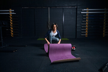 Man rolling up yoga mat