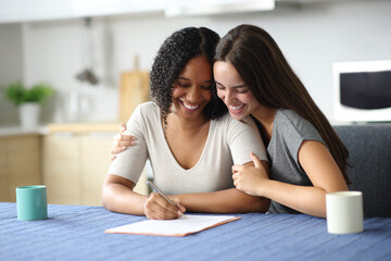 Happy interracial lesbian couple signing paper contract