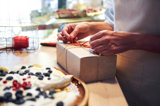 Woman tying a ribbon on a cake box in a confectionery shop