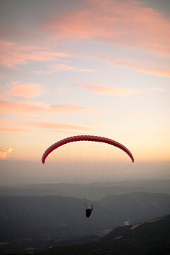 Paraglider flying with mountains in the background during sunset