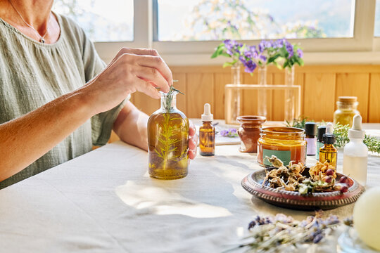 Woman preparing rosemary oil for treatment at table
