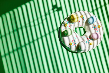 Easter doughnut decorated with chocolate eggs on green table