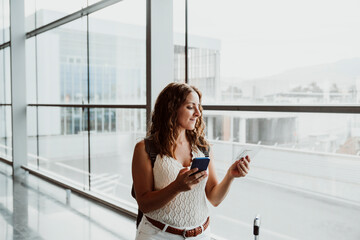 Smiling mature woman doing online check-in through smart phone at airport