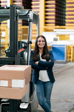 Confident woman standing in logistics center, with arms crossed
