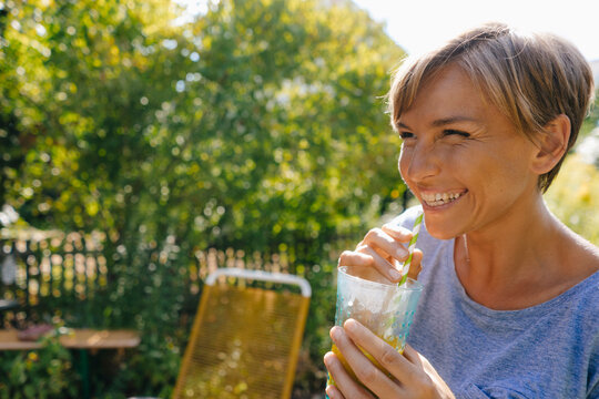 Happy woman drinking a sof drink in garden