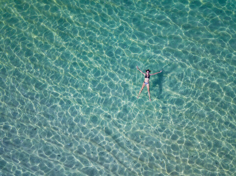 Indonesia, Bali, Melasti, Aerial view of Karma Kandara beach, woman floating on water