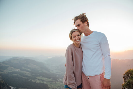 Switzerland, Grosser Mythen, portrait of happy young couple standing in mountainscape at sunrise - Powered by Adobe