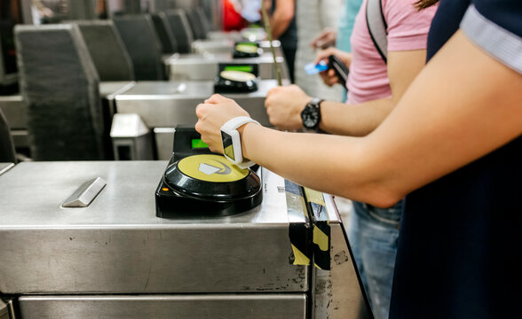 Young woman paying with her smartwatch on the subway, partial view