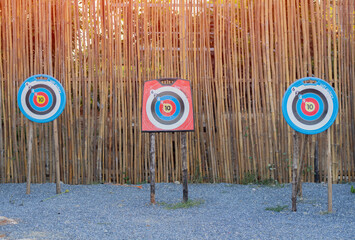 Three archery targets against a bamboo wall backdrop.