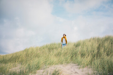 Mature woman relaxing in the dunes, enjoying the wind