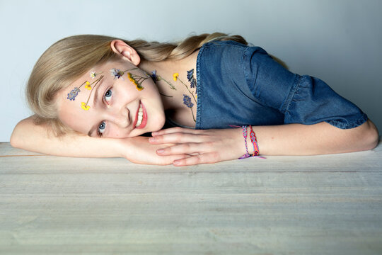 Portrait of smiling blond girl with tattoo of pressed flowers on her face